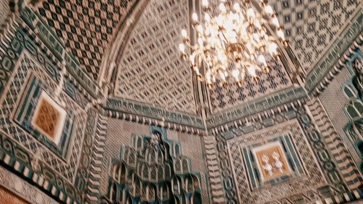 Ornate tiled interior of a domed mausoleum at Shah-i-Zinda with a chandelier